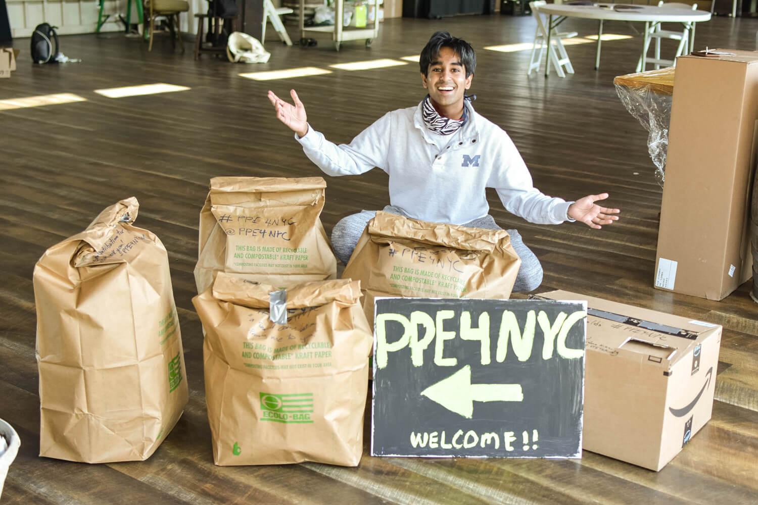 Krishna Koka, the CEO of PPE4ALL, squats by a couple of bags of PPE